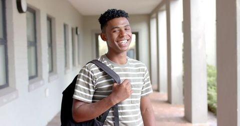 Smiling Teen Student Holding Backpack in Open Corridor - Download Free Stock Images Pikwizard.com