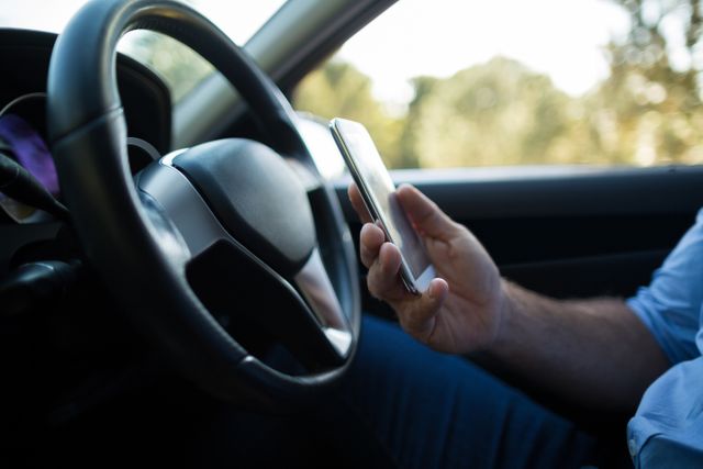 Mid section of man using mobile phone in car