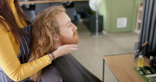Barber is giving a haircut to a redheaded man with a beard in a salon. Suitable for illustrating concepts related to male grooming, barbershop services, hair care routines, and hairstyling professionals. Can be used for promoting barbershop services, products, and styling techniques.