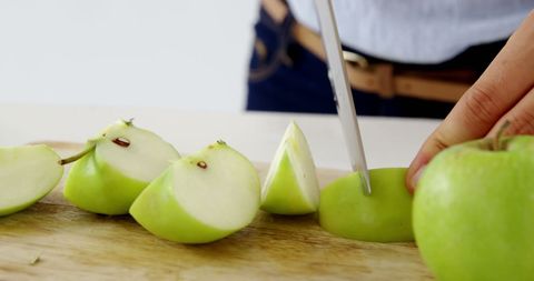 Slicing fresh green apple on cutting board, healthy snack preparation