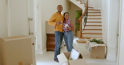 Couple celebrating new home with coffee among moving boxes