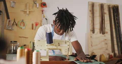 African american craftsman working with sewing machine in workshop