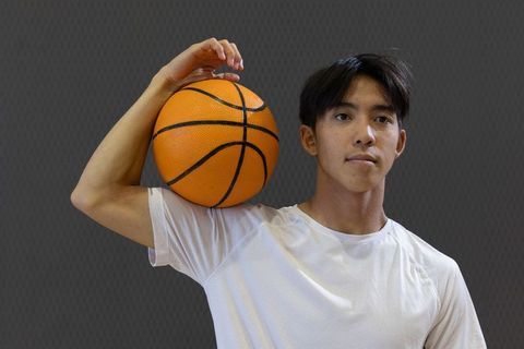 Asian male athlete holding basketball on shoulder portrait for sports and fitness branding