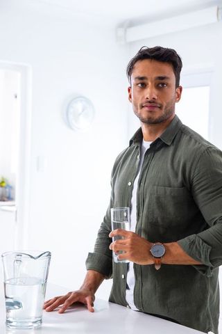 Man Enjoying Refreshing Drink in Modern White Kitchen