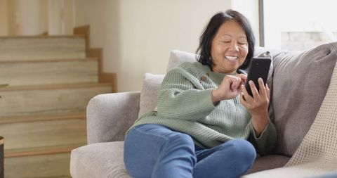 Senior Woman Relaxing on Sofa with Smartphone