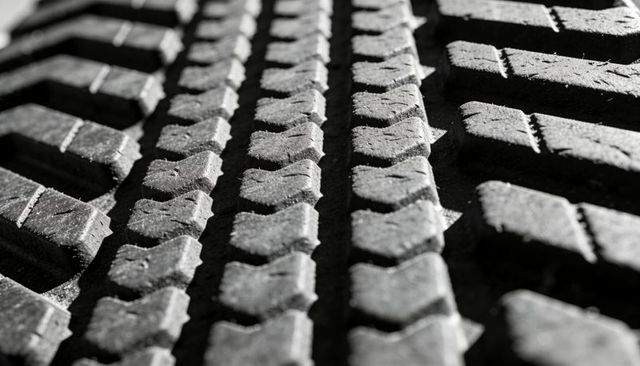 Macro tire tread pattern revealing textured rubber blocks, grooves and dust details