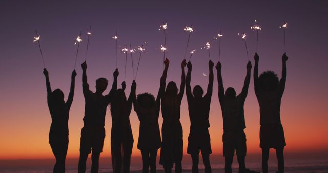 Group of friends celebrating with sparklers at the beach during sunset. Perfect for themes related to friendship, celebrations, summer nights, travel adventures, and joyful moments. Ideal for social media posts, travel blogs, advertisements, or any project highlighting togetherness and fun.