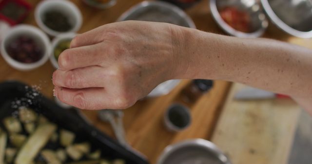 Close-up of Hand Seasoning Vegetables with Salt in Kitchen - Download Free Stock Images Pikwizard.com