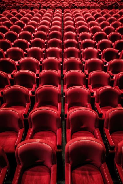 Rows of empty red seats fill a theater, awaiting an audience. The vibrant red chairs set the stage for an immersive cultural or entertainment experience.