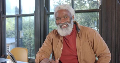 Friendly Senior Man in Home Office Writing by Window