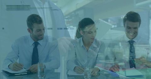 Corporate team taking notes around glass table with tablet reflection double exposure