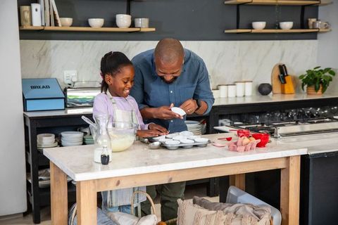 African american father teaching daughter baking muffins in farmhouse kitchen