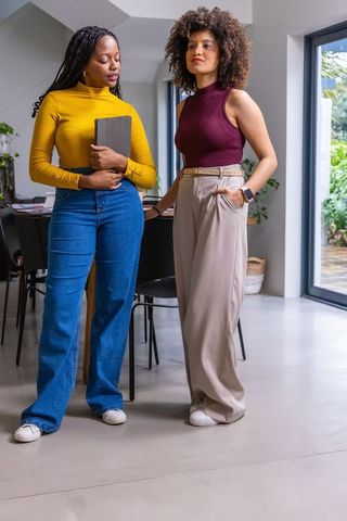 African american women standing in modern home office holding tablet collaborating