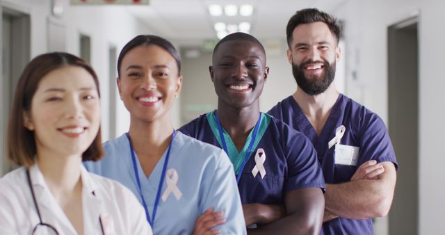 Image portrait of diverse group of smiling medical workers with cancer ribbons in hospital corridor. Hospital, medical and healthcare services.