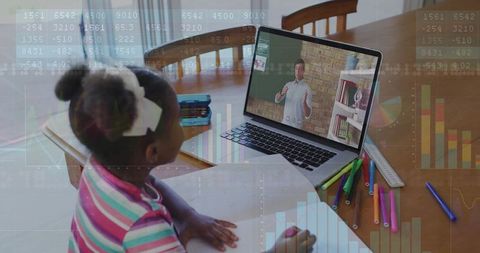 Young girl studying remotely at dining table with laptop, workbook and colorful markers