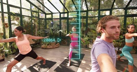 Man Filming Group Practicing Yoga in Sunlit Glasshouse with AR Fitness Overlay