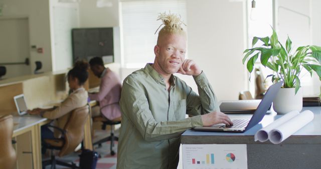 Portrait of happy albino african american businessman using laptop in creative office - Download Free Stock Photos Pikwizard.com