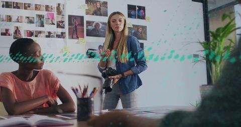 Creative director directing camera work during studio meeting with mood board and prints