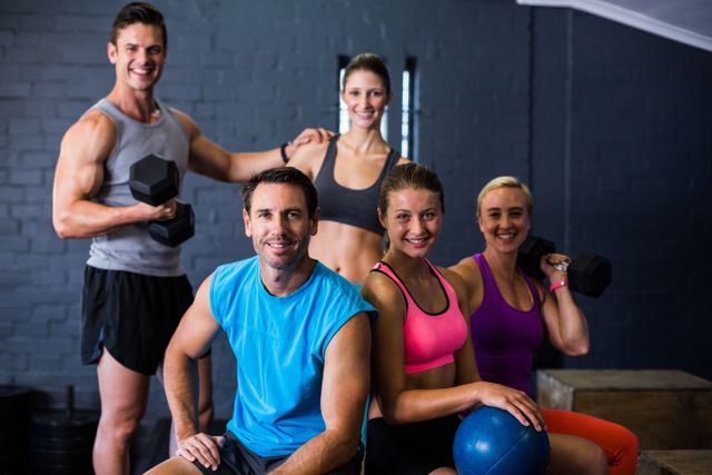 Group of happy male and female athletes in a fitness studio, showcasing teamwork and motivation. Ideal for promoting gym memberships, fitness programs, healthy lifestyle campaigns, and sportswear advertisements.