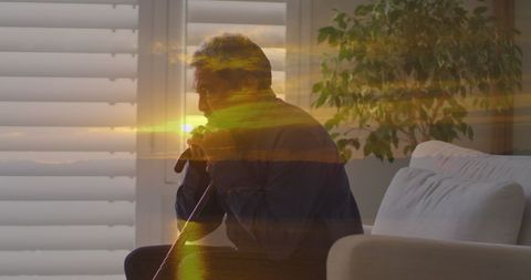 Senior man reflecting with walking cane and sunset overlay