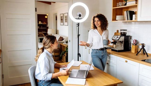 Presenting Host Recording Podcast in Home Kitchen with Ring Light and Laptop