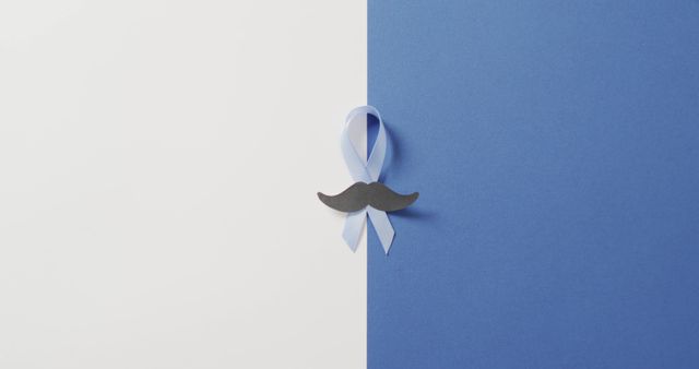 Image of paper moustache and pale blue prostate cancer ribbon on white and blue background. medical and healthcare awareness support campaign symbol for prostate cancer.