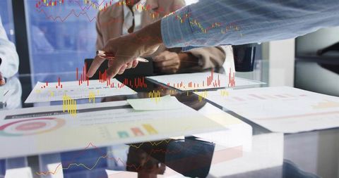 Business Team Analyzing Financial Charts Overlaid on Meeting Documents and Reports