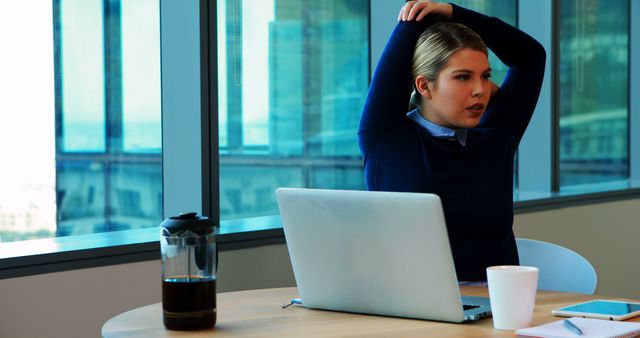 Businesswoman Stretching in Office Next to Laptop and Coffeemaker - Download Free Stock Images Pikwizard.com