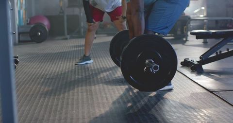 Male partner deadlift lifting with spotter on rubber mat strength training gym workout