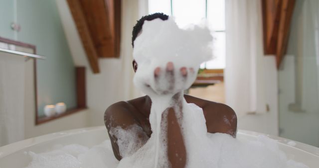 Smiling african american attractive woman taking bath and blowing out foam in bathroom - Download Free Stock Photos Pikwizard.com