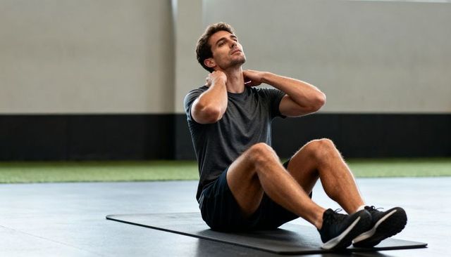 Man doing seated crunches on gym mat building core strength and athletic conditioning