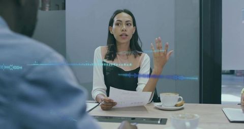 Businesswoman leading meeting presenting data with hand gesture in modern boardroom