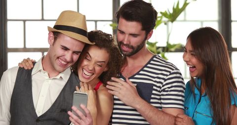 Diverse group of friends laughing over smartphone moment