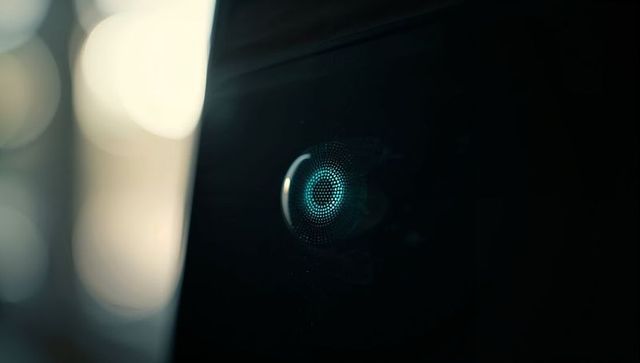 Minimalist smart speaker emitting teal led ring on glossy black panel with warm bokeh
