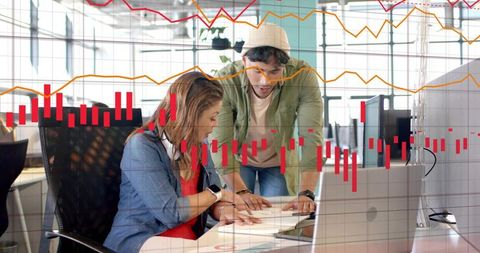 Young Professionals Collaborating Over Data and Laptop in Modern Office with Graph Overlays