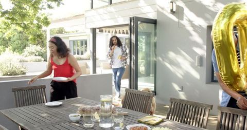 Friends setting up birthday party outdoors on bright day