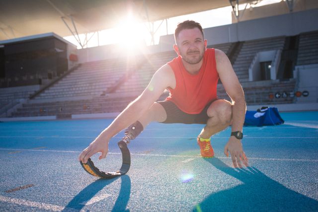 Caucasian disabled male athlete with prosthetic leg training, stretching. professional runner training at sports stadium.
