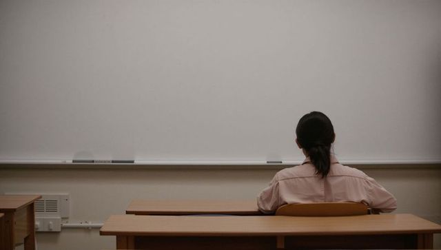 Female student facing large whiteboard in empty classroom back view solo study atmosphere
