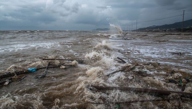 Stormy ocean waves and debris-scattered beach shoreline