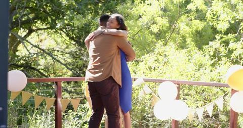 Couple embracing in sunlit garden engagement celebration