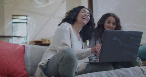 Mother and Daughter Laughing on Sofa Using Laptop for Online Learning and Family Bonding