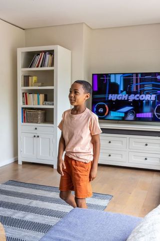 African boy watching high score on tv in modern bright living room, casual gaming moment