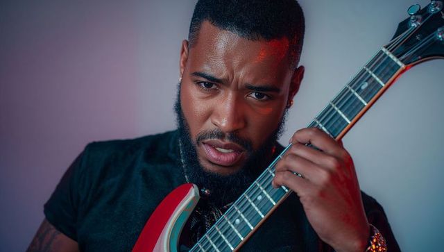 Expressive male musician with electric guitar in artistic lighting