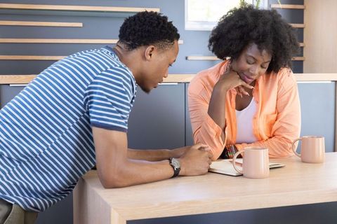 African american coworkers collaborating at kitchen counter reviewing notebook and planning