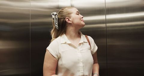 Young woman checking elevator floor indicator with hair scarf