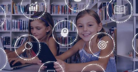 Girls Collaborating with Tablet and Laptop in Library Using Digital Learning and Study Apps