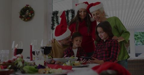 Family in Santa Hats Enjoy Holiday Meal and Smartphone