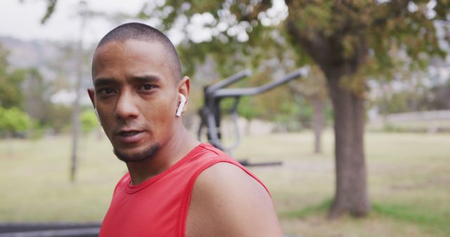 This image shows a man with earbuds in a park while exercising. Ideal for promoting active lifestyles, outdoor workouts, fitness apps, sports gear, or health-related content.