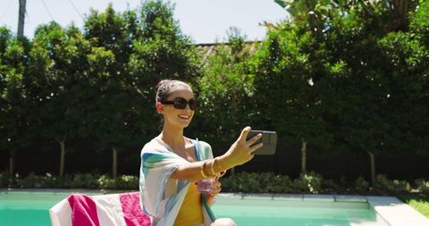 Woman Taking Selfie Near Poolside Showcasing Sunny Relaxation and Leisure