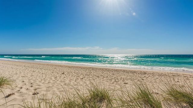Turquoise ocean waves over sunlit golden sands